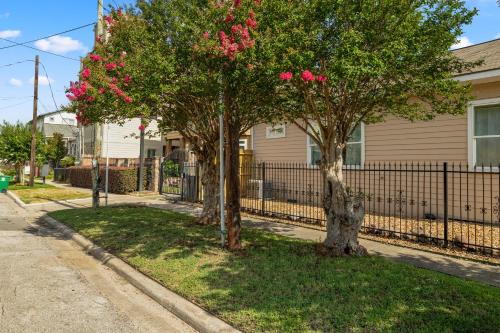 two trees with pink flowers in front of a fence at Loft Style Studio In The Heart of D'Arts District in Houston