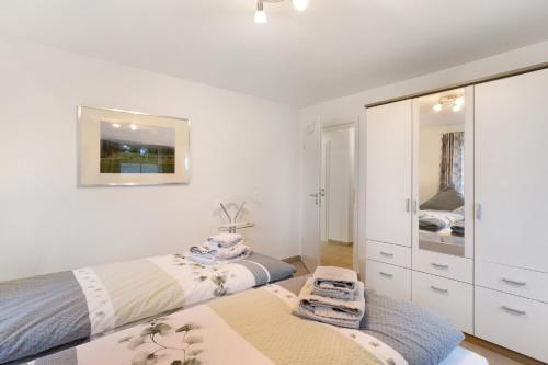a white bedroom with two beds and a mirror at Ferienhaus Wasserfall in Bestwig