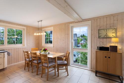 a dining room with a table and chairs and windows at Ferienhaus Wasserfall in Bestwig