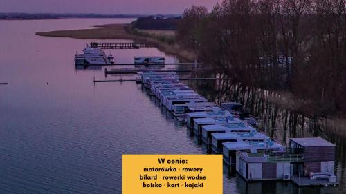 a marina with boats parked in the water at HT Houseboats - domki na wodzie - sauna, motorówka, rowerki wodne in Mielno