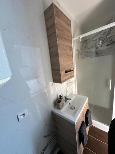 une salle de bain blanche avec un lavabo et une douche dans l'établissement Duplex Cosy en Cœur de Ville, à Lunel
