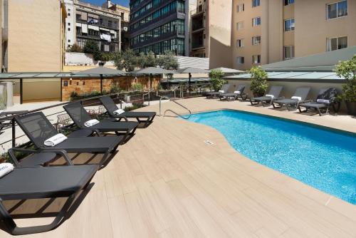 a swimming pool with lounge chairs next to a building at HCC Montblanc in Barcelona