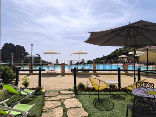 een patio met stoelen en een parasol naast een zwembad bij L'Infinito Tanca Piras in Nebida