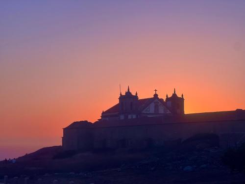 a silhouette of a building on a hill at sunset at Coastal Breeze Villa in Sesimbra in Sesimbra