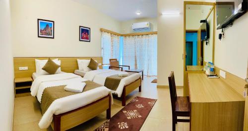 a hotel room with two beds and a television at Kaibalya Bliss in Bhubaneshwar