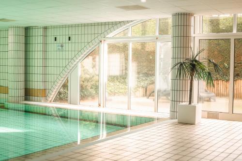 a swimming pool with a potted plant in a building at WestCord Hotel Schylge in West-Terschelling