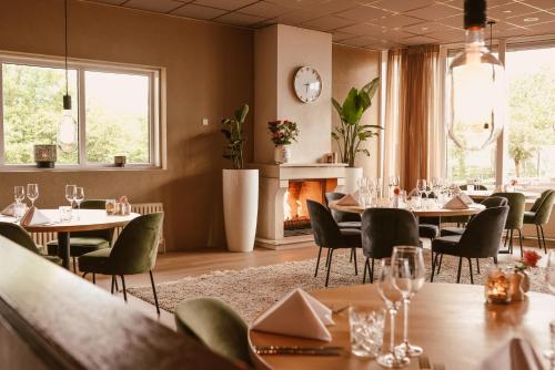 a restaurant with tables and chairs and a fireplace at WestCord Hotel Schylge in West-Terschelling