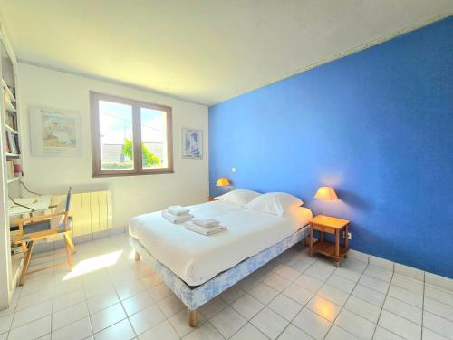 - une chambre bleue avec un lit, une table et une fenêtre dans l'établissement Le Ligno - Maison Néo-bretonne mer et plages, à Saint-Gildas-de-Rhuys