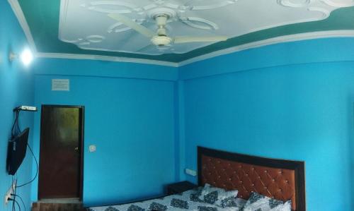 a bedroom with blue walls and a ceiling at Sheetal Restaurant in Mussoorie