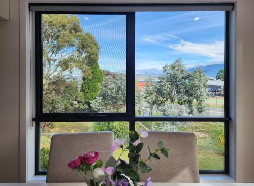 a window with two chairs and a vase with flowers at Modern New Home near Howrah Beach in Howrah