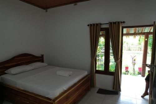 a bedroom with a bed and a large window at Coconut Scar Reef Homestay in Maluk