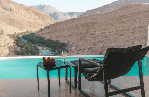 a chair and a table with a glass of wine at Wadina resort Wadi Bani Khalid in Muqal