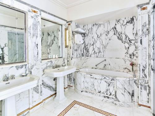 a white bathroom with two sinks and a tub and a mirror at Le Meurice – Dorchester Collection in Paris