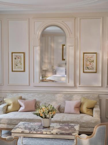 a living room with a couch and a mirror at Le Meurice – Dorchester Collection in Paris
