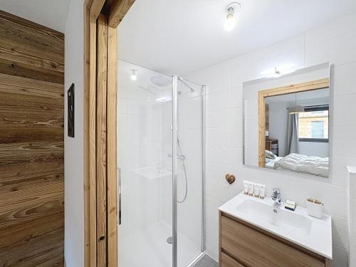 une salle de bain blanche avec une douche et un lavabo dans l'établissement Celadon - appartement- 4 pers - proche centre, aux Gets