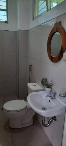 a bathroom with a toilet and a sink and a mirror at Bayay ni Mayang (Fully furnished apartment) in Surigao