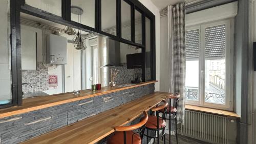 - un bar avec tabourets dans une pièce dotée de fenêtres dans l'établissement Charmant cocon tout équipé, à Clermont-Ferrand