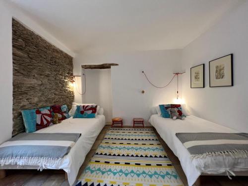 - 2 lits dans une chambre avec un mur en pierre dans l'établissement Villa Christelle avec piscine Cap Corse, à Centuri
