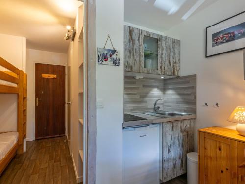 Elle comprend une petite cuisine avec des placards en bois et un évier. dans l'établissement Studio rénové avec balcon, parking et proche pistes à Val-d'Isère - FR-1-694-287, à Val dʼIsère