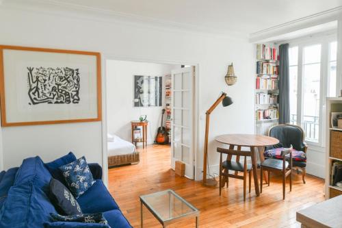 un salon avec un canapé bleu et une table dans l'établissement Appartement lumineux à Paris by Weekome, à Paris