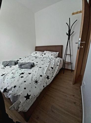 a bedroom with a bed with a black and white comforter at Apartman Višnja in Gornja Toplica