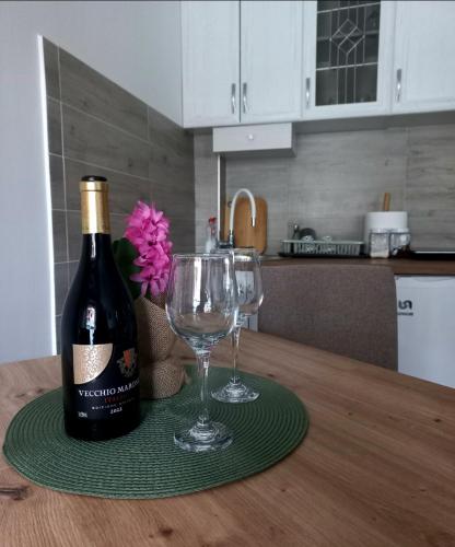 a bottle of wine and two glasses on a table at Apartman Višnja in Gornja Toplica