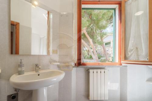 a white bathroom with a sink and a window at La Rondine su Seccheto - Goelba in Seccheto