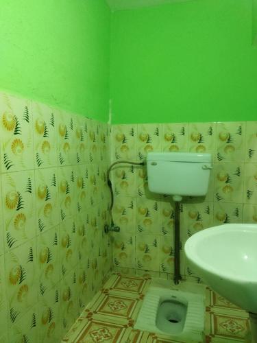a green bathroom with a toilet and a sink at Sheetal Restaurant in Mussoorie