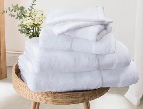 a stack of white towels sitting on a stool at La Bergerie à Palleau, Les Blés Dorés et Les Graines de Lin à Corgengoux, proches de Beaune et de ses villages viticoles in Palleau