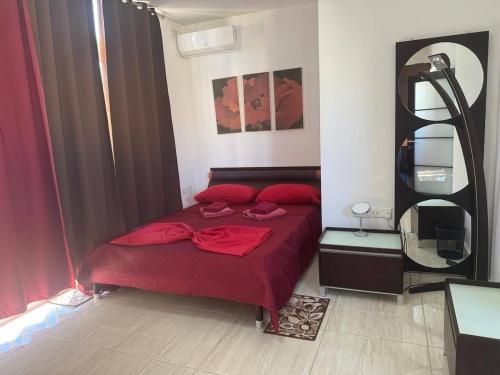 a bedroom with a red bed and a mirror at Central Penthouse Suite BBQ&Hot Tub 5Min Walk2Sea in St Paul's Bay