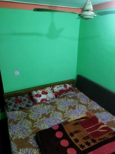 a bed in a room with a green wall at Sheetal Restaurant in Mussoorie