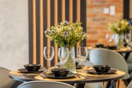 stół ze szklankami i wazonem z kwiatami na nim w obiekcie Seaside Loft B009 ze SPA- Posesja Plażowa - Holiday City w Grzybowie