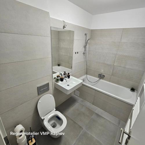 a bathroom with a toilet and a sink and a tub at Apartament Rasnov VMP Free parking in Râşnov
