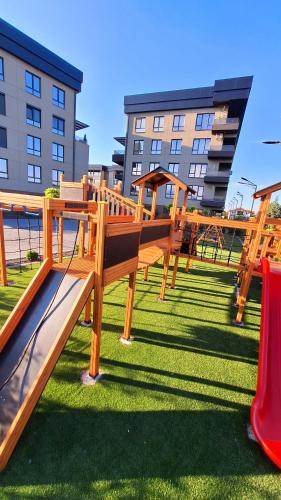 a park with wooden benches and a red slide at Kjara Apartment-Airport in Petrovec