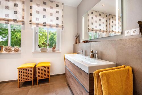 a bathroom with a sink and two yellow chairs at Ferienwohnung am Kronsberg in Bösel