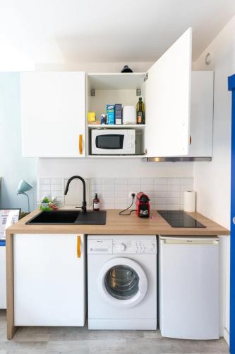 une cuisine avec des armoires blanches et une machine à laver dans l'établissement Le Coysevox - Joli studio tout confort pentes de la Croix Rousse, à Lyon