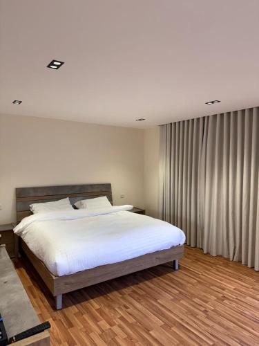 Un dormitorio con una cama grande con sábanas blancas. en Malak hostel, en Al Ula
