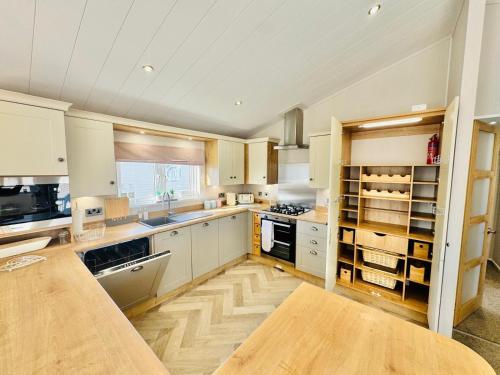 a large kitchen with white cabinets and a wooden floor at The Pink Lady in Walton-on-the-Naze