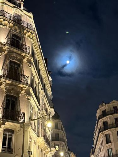 un bâtiment la nuit avec la lune dans le ciel dans l'établissement Villa B, à Lyon