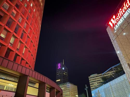 un grand bâtiment avec un panneau violet dessus la nuit dans l'établissement Villa B, à Lyon
