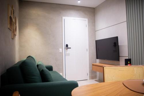 a living room with a green couch and a television at Apartamento Loft 02 Lazer Completo in Belo Horizonte