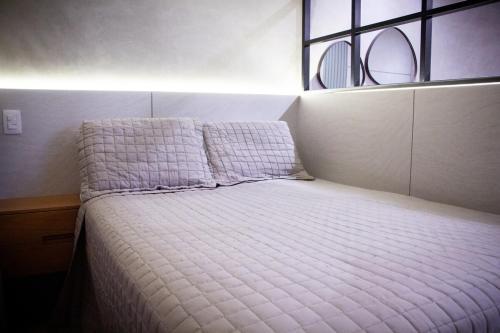 a small bedroom with a bed with a window at Apartamento Loft 02 Lazer Completo in Belo Horizonte