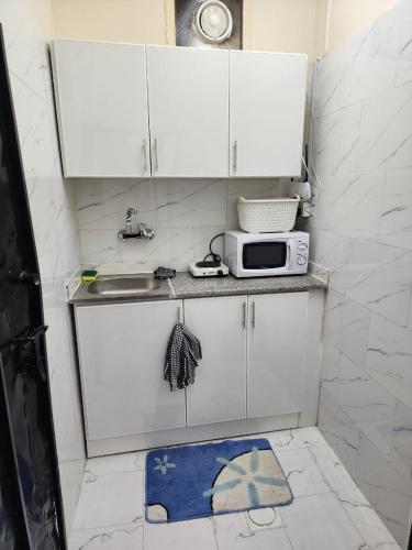 a small kitchen with a sink and a microwave at Furnished hone stay villa with attached bathroom with balcony in Al 'Ayn