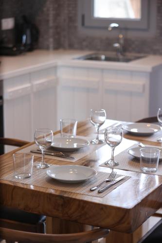a wooden table with plates and wine glasses on it at The George Villas with Private Pool, & Suite with Jacuzzi, close to Mykonos Town - Chora in Mikonos