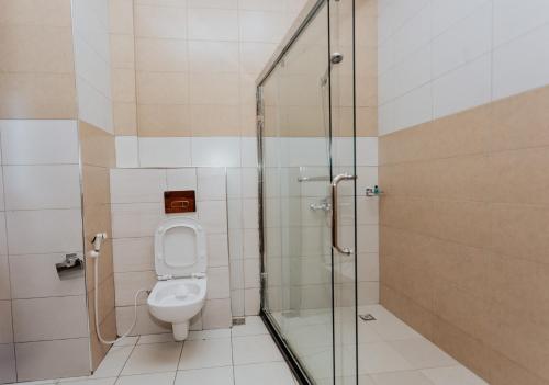 a bathroom with a toilet and a glass shower at La Mama Hotel in Uru