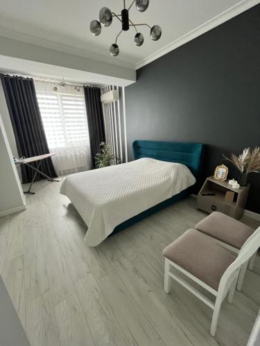 Un dormitorio con una cama blanca y una silla. en Central Luxe 2BR, en Chişinău