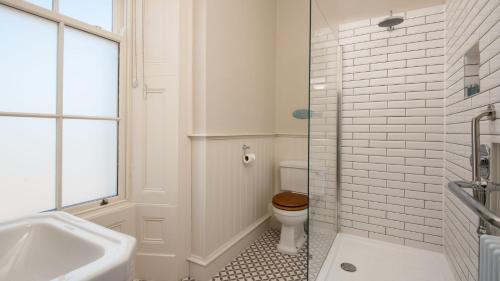 a white bathroom with a toilet and a sink at Cambridge House in Holy Island