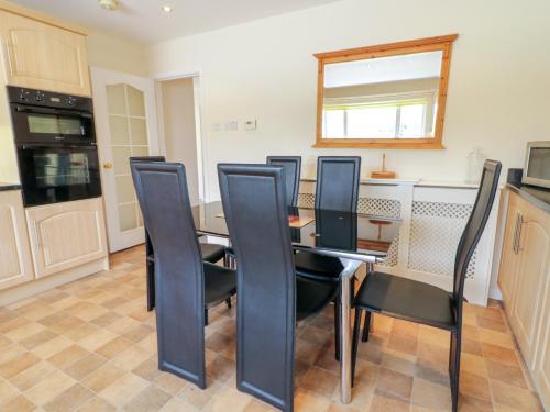 a dining room with a table and black chairs at 3 Warke Place in Coleraine