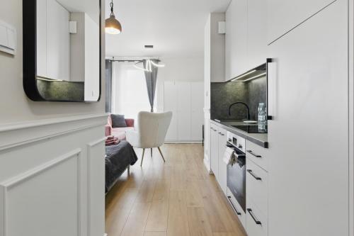 a kitchen and living room with white cabinets at Stylowy apartament z balkonem i panoramą miasta in Siedlce