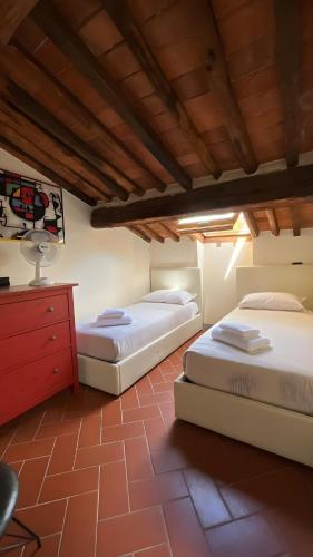 two beds in a room with a red dresser at La terrazza di Sofia in Lucca